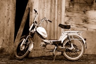 A vintage motorcycle with leather saddlebags resting beside a rustic barn.