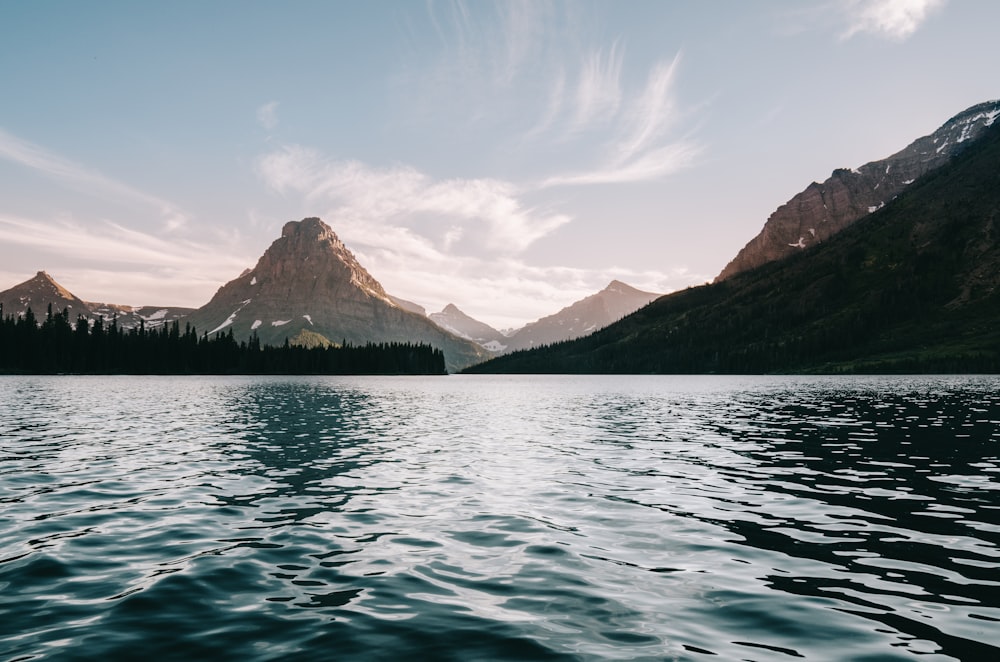 body of water near body trees and mountain