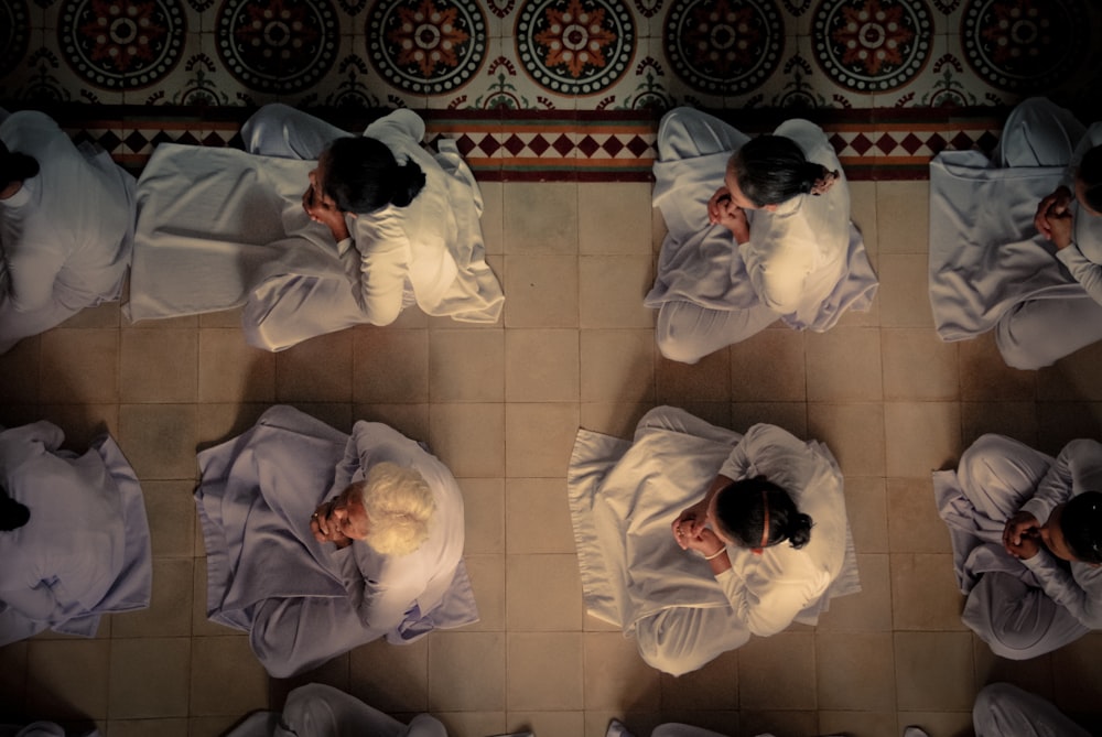 men sitting on white square tile floor