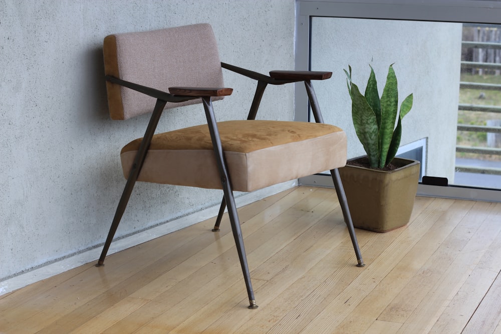 brown fabric padded armchair beside green snake plant inside room