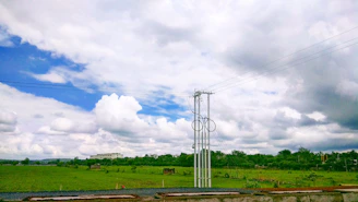 A sleek battery energy storage facility set against a clear blue sky with green fields surrounding it.