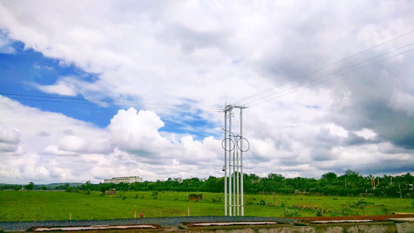 A sleek battery energy storage facility set against a clear blue sky with green fields surrounding it.
