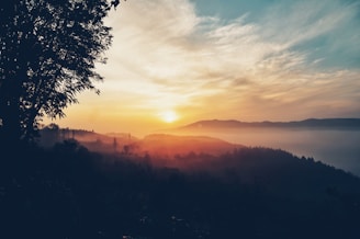 A vibrant sunrise over a misty mountain trail with a lone hiker carrying a backpack.