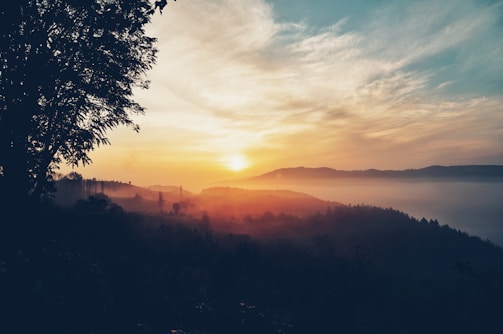 A vibrant sunrise over a misty mountain range with a lone hiker.