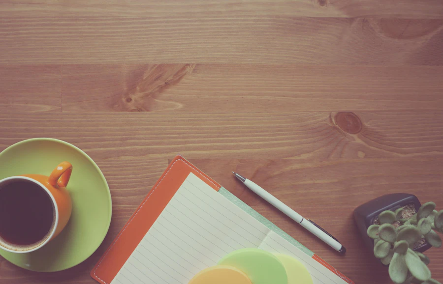 A notebook, pen and coffee cup on a desk