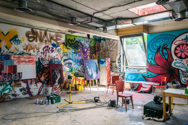 Vibrant artist studio with graffiti walls, canvases on easels, and painting supplies.