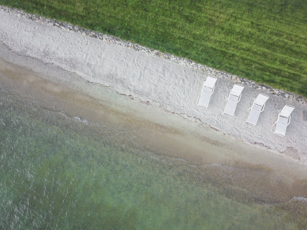 birds eye view of four white lounge chairs on white sand