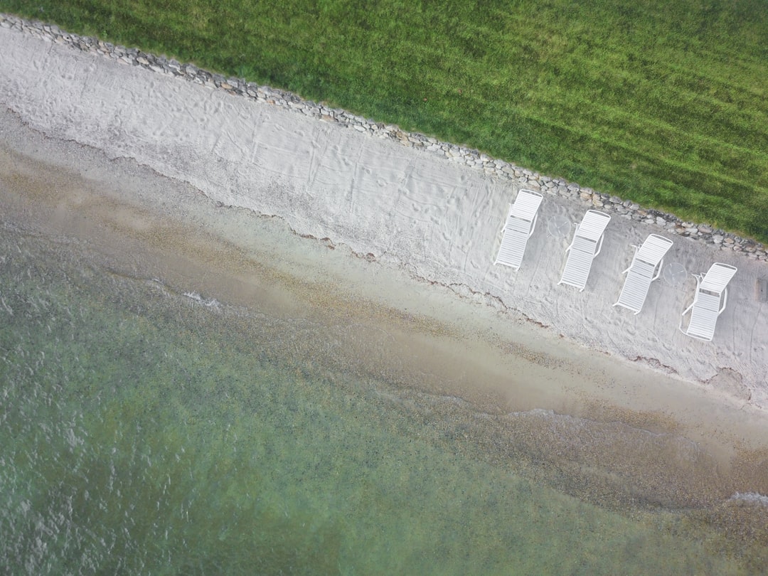 birds eye view of four white lounge chairs on white sand