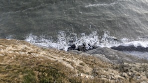 Cinematic aerial perspective of a coastal shoreline with waves crashing against rocks