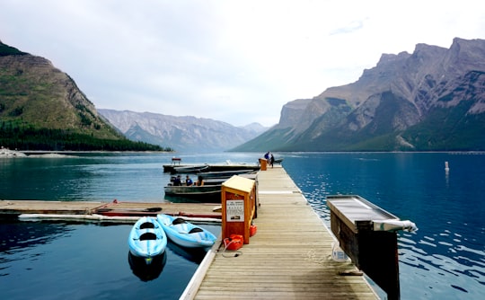 two blue kayaks beside brown wooden port in Lake Minnewanka Canada