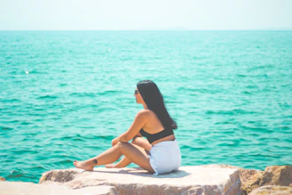 A serene woman sitting peacefully by the turquoise waters of Cancún, bathed in soft natural light.