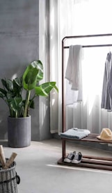 gray dress shirt hang on brown wooden rack in front of window with white curtain