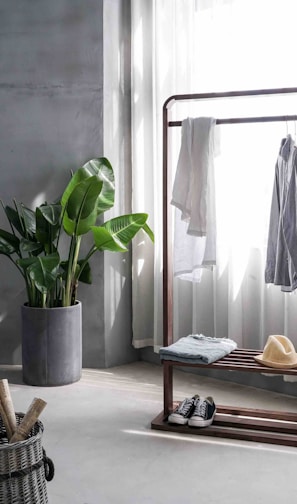 gray dress shirt hang on brown wooden rack in front of window with white curtain