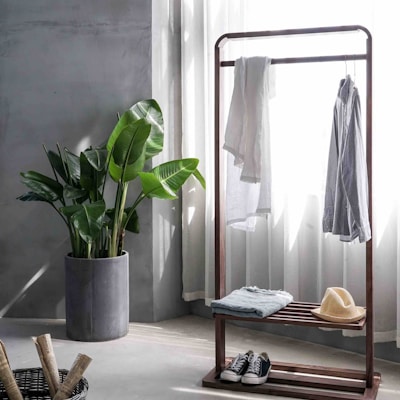 gray dress shirt hang on brown wooden rack in front of window with white curtain