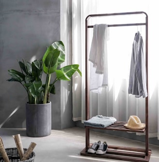 gray dress shirt hang on brown wooden rack in front of window with white curtain