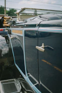 Side view of a vintage car with glossy blue paint reflecting the garage surroundings.
