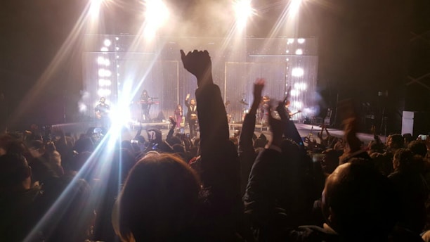 A lively concert scene with a tribute band performing on stage, capturing the energy of the audience.