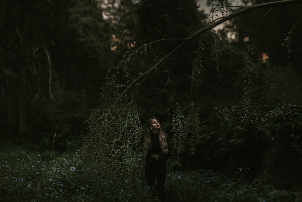 a woman standing in the middle of a forest