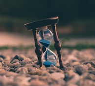 selective focus photo of brown and blue hourglass on stones
