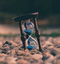 selective focus photo of brown and blue hourglass on stones