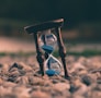 selective focus photo of brown and blue hourglass on stones