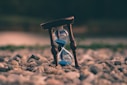 selective focus photo of brown and blue hourglass on stones