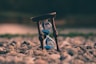 selective focus photo of brown and blue hourglass on stones