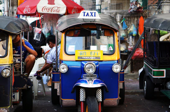 A colorful tuk tuk parked by a bustling street market, ready for a solo traveler.