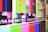 A series of multicolored horizontal and vertical bars are displayed, reminiscent of a television test pattern. Various colors such as green, blue, pink, and yellow are present along with white text containing alphanumeric codes.