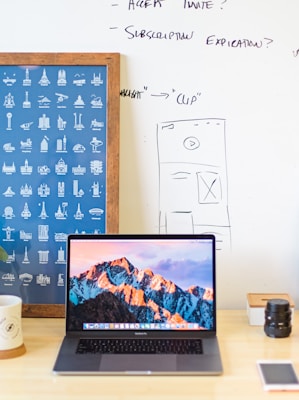 MacBook Pro on brown wooden table beside white mug