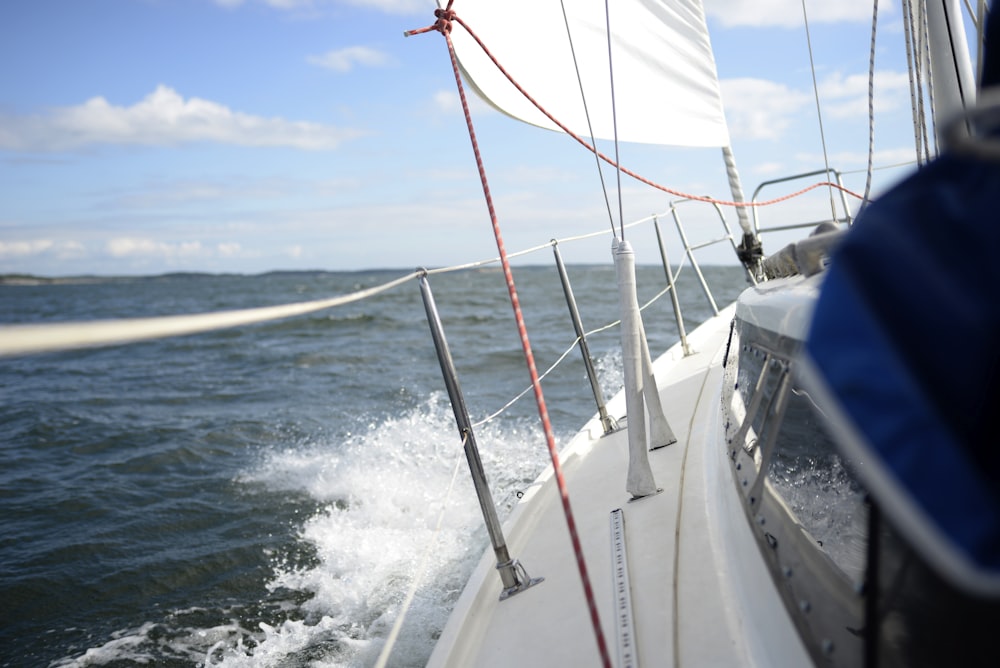 Weißes und blaues Boot, das tagsüber auf dem Wasser segelt