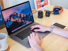 MacBook Pro turned on beside white ceramic mug