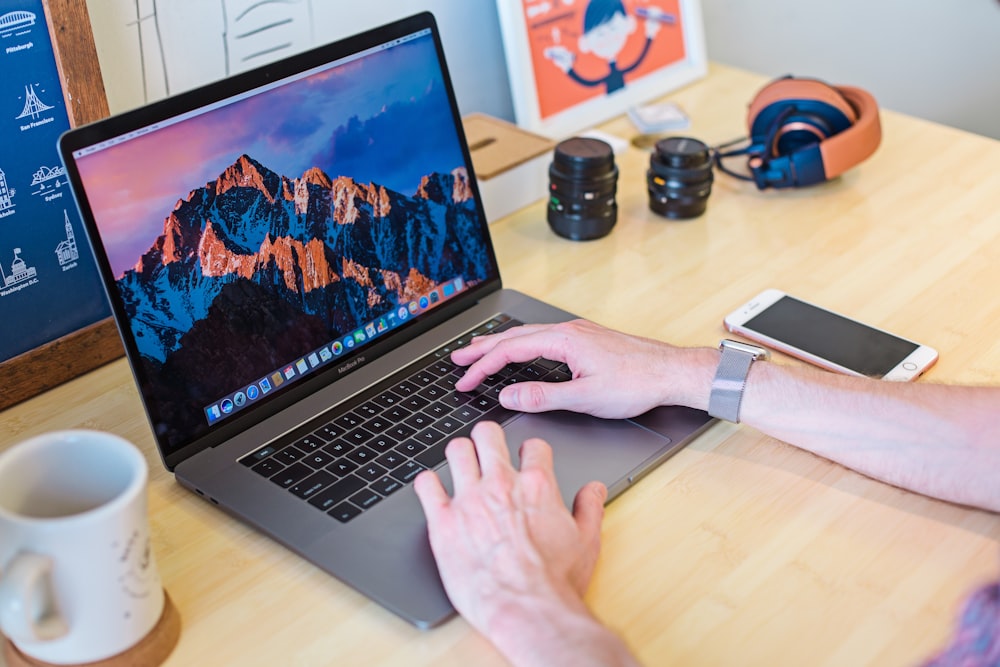 MacBook Pro turned on beside white ceramic mug