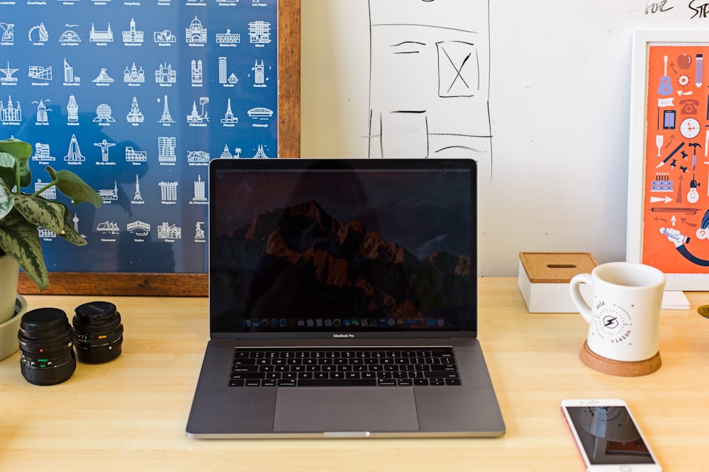 Macbook Pro on table near white mug and PRODUCT RED iPhone