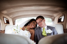 photo of smiling wedding coupe sitting inside vehicle