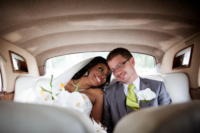 Bride and groom smiling in the back of a limousine