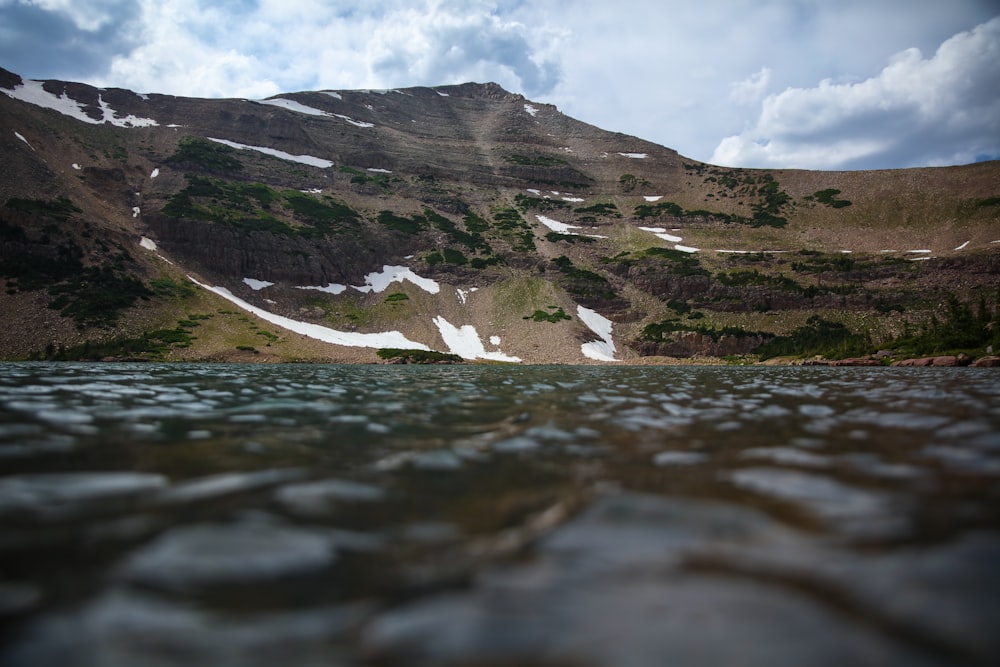 low angle photography of body of water and mountain