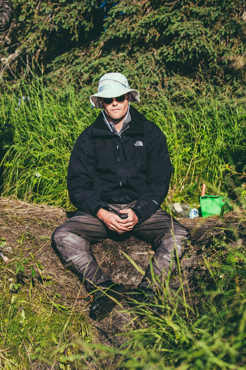 man in black jacket and black pants sitting on brown rock