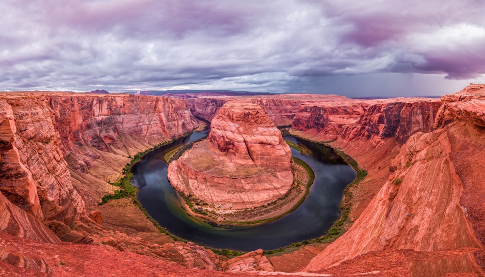 brown mountain with river under cloudy sky