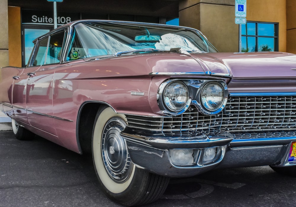 pink classic car parked near concrete building