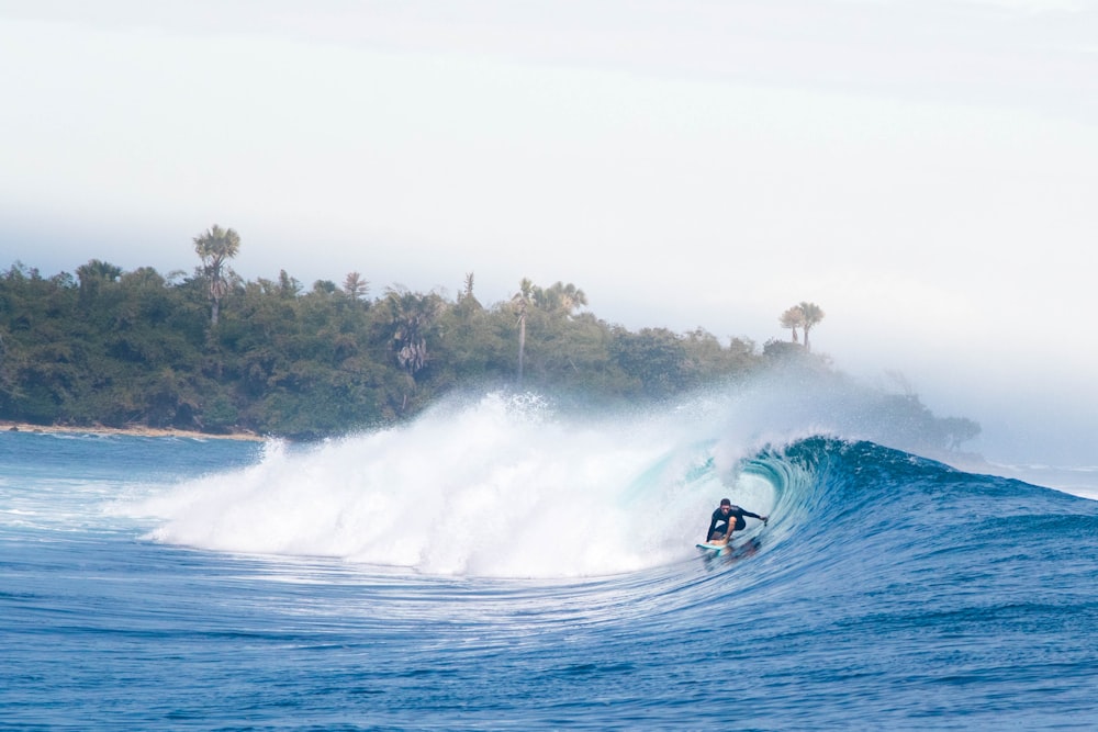 man surfing on big waves under white sky