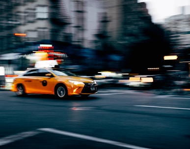 orange coupe running on gray street during daytiem