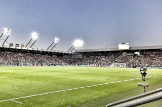 A vibrant photo of a local football match with players celebrating a goal under bright stadium lights.
