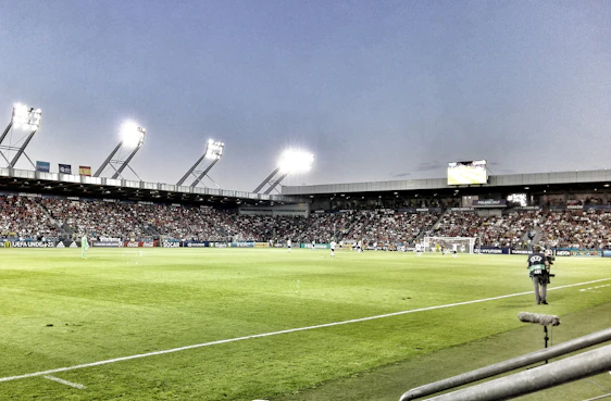 A vibrant photo of a local football match with players celebrating a goal under bright stadium lights.