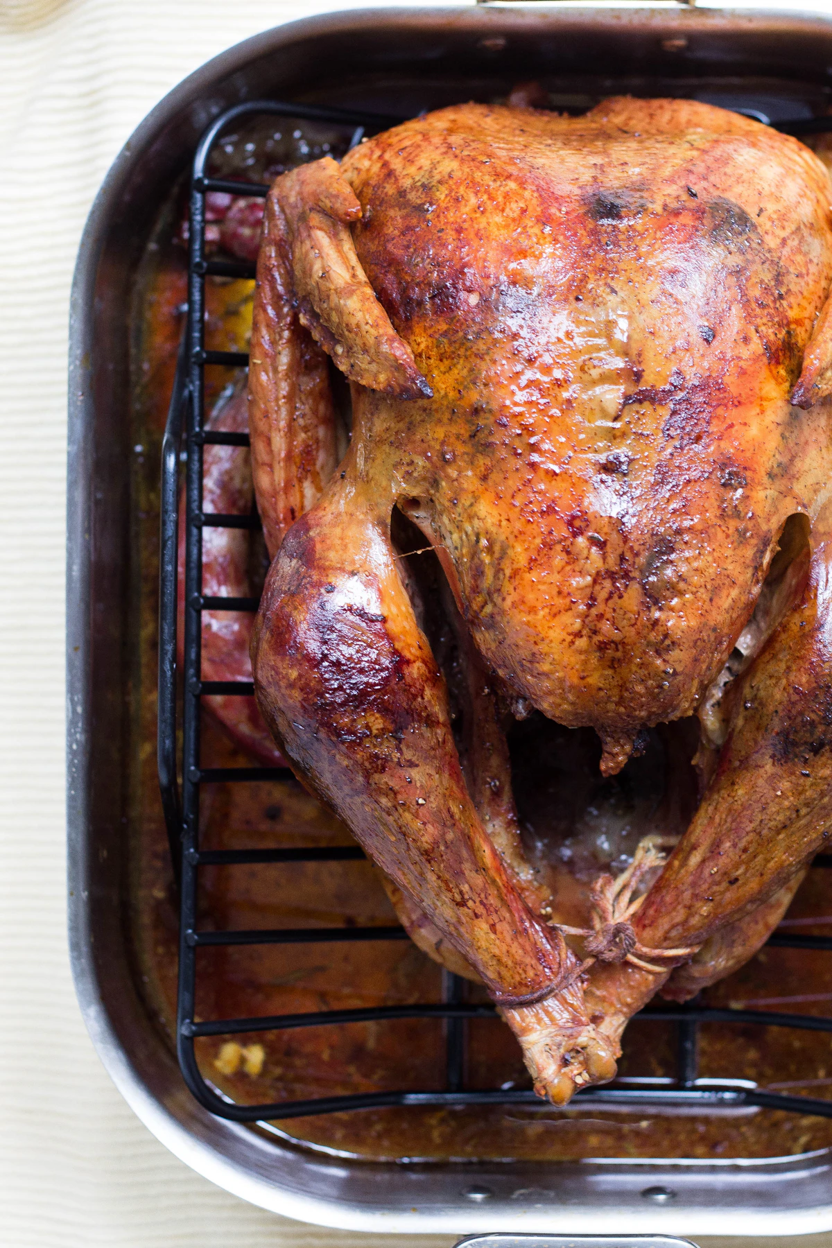 A whole roast chicken resting in a roasting pan