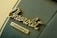 A close-up view of a vintage emblem featuring the word Chevrolet in stylized cursive script, set above a smaller rectangular section with the word Camaro. The background is a muted green, hinting at age and nostalgia.