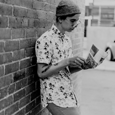 grayscale photo of man leaning on wall