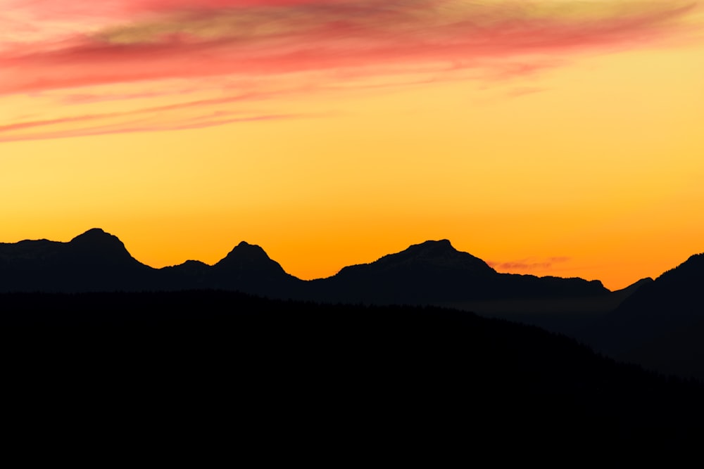 Silhouettenfotografie von Bergen unter der goldenen Stunde