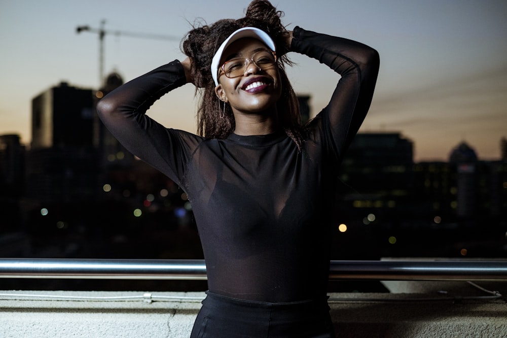 woman holding her hair leaning on white and gray guardrail during nighttime