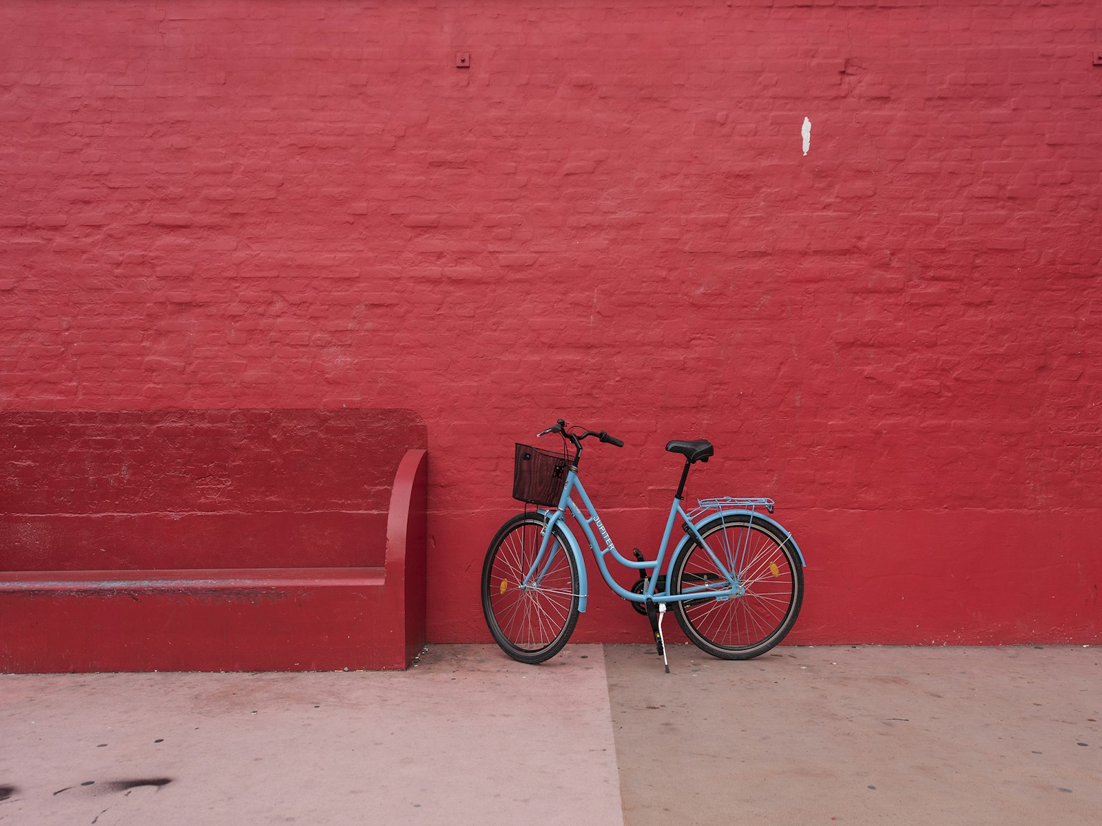 Un vélo bleu clair devant un mur de briques rouges